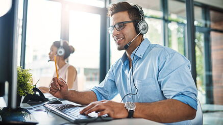 Ein Mann mit Headset sitzt an einem Schreibtisch